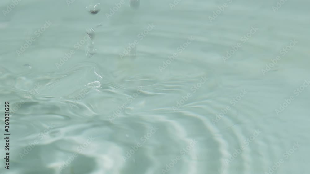 A small puddle of water with drops falling from the sky. Scene is calm and peaceful, as the drops of water create a serene atmosphere