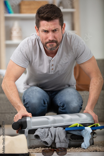 Fotografi a man trying to close valise