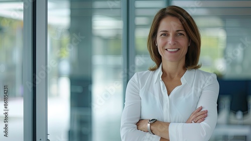 Free Download A smiling woman in a white shirt stands confidently with arms crossed in an office setting - GFXLoad