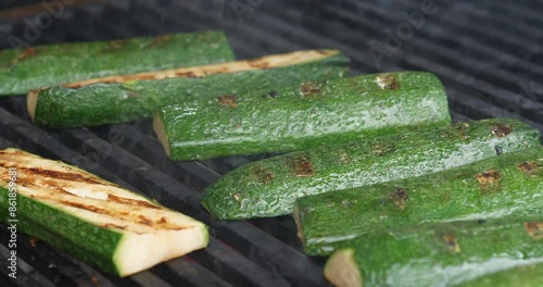 Zucchini or green vegetable marrow are grilled over an open fire. Cook turns the zucchini slices over to ensure even cooking on all sides