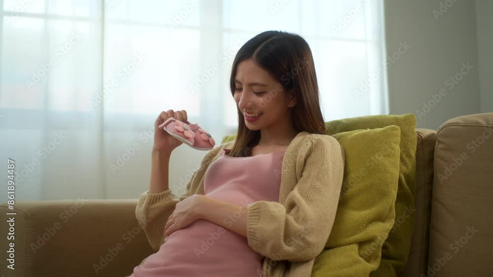Happy pregnant woman looking at tiny kids pink shoes while caressing her belly at home, happy motherhood waiting for childbirth, family planning and pregnancy with insurance for child health.
Happy pregnant woman looking at tiny kids pink shoes while caressing her belly at home, happy motherhood waiting for childbirth, family planning and pregnancy with insurance for child health.