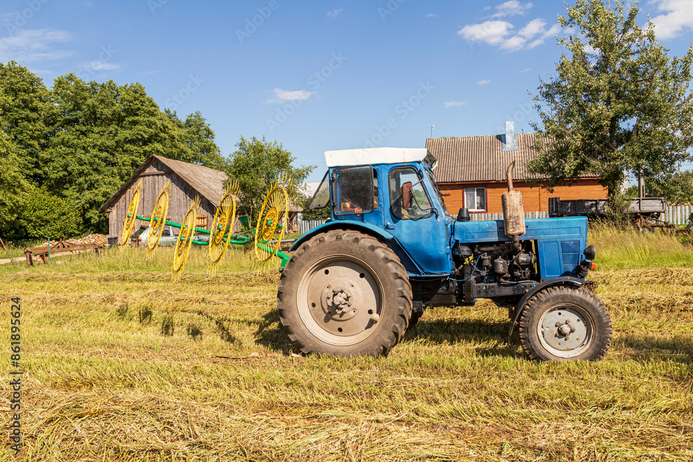 natural lighting. The driver of a blue tractor cleans hay and oats. close-up natural lighting. The driver of a blue tractor cleans hay and oats. close-up