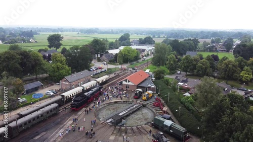 Beekbergen, the Netherlands - August 6th, 2023: Ascending drone footage of people lining up to see a steam locomotive on the local marshalling yard before it leaves on a trip to nearby Dieren. photo