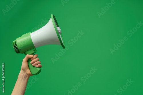 Hand holding a megaphone against a green background, perfect for conveying messages with attention-grabbing communication. Ideal for activism, marketing, or raising awareness