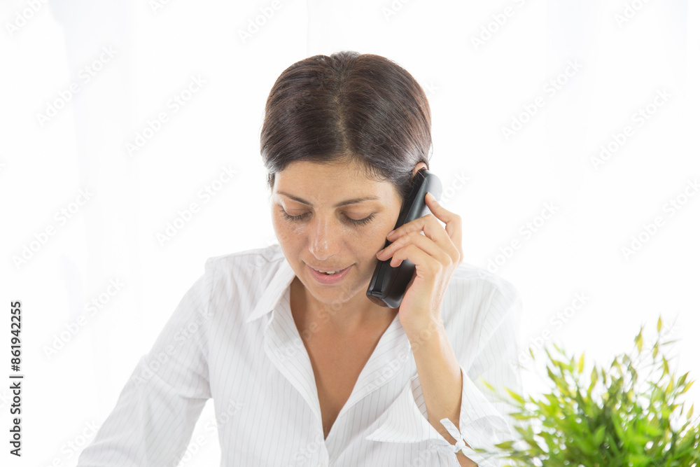 Good business talk. Cheerful young beautiful woman in glasses talking on mobile phone and using laptop with smile while sitting at her working place Good business talk. Cheerful young beautiful woman in glasses talking on mobile phone and using laptop with smile while sitting at her working place
