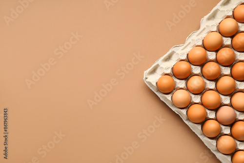 Chicken eggs in cardboard box on beige background photo