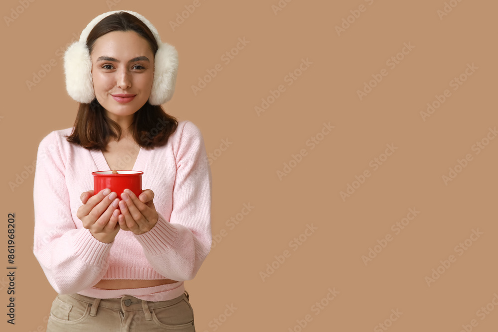 Beautiful young woman with cup of hot mulled wine on brown background Beautiful young woman with cup of hot mulled wine on brown background
