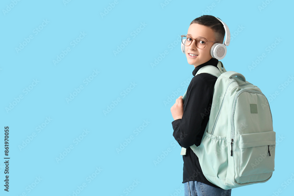 Cute schoolboy with headphones and backpack on blue background Cute schoolboy with headphones and backpack on blue background
