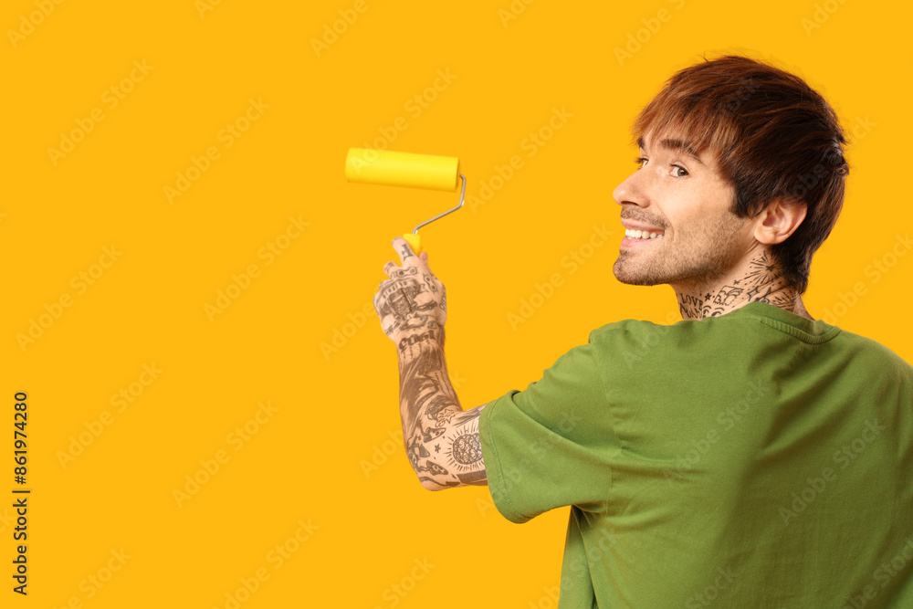 Young man with paint roller on yellow background Young man with paint roller on yellow background