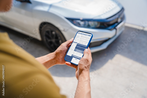 Man fills out a car insurance form after a car accident. Comprehensive motor insurance covers car damage. He files a claim report, speaking with an adjuster to understand his coverage and deductible. photo