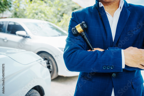 Fotografía businessman in a suit and a lawyer, holding a wooden gavel, stand in front of a car, discussing legal aspects like citations, liability, and negligence related to a traffic violation