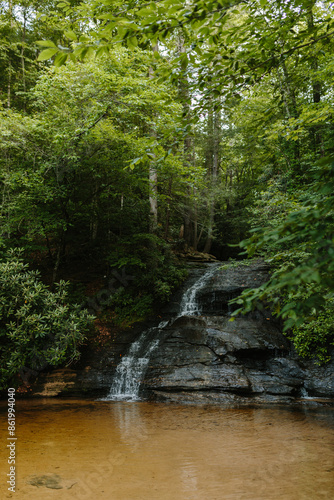 Beautiful large waterfall between green trees in the mountains. Mountain landscape with a waterfall on a summer day. Wildcat Waterfall, Great Smokey Mountains, South Carolina, USA. 