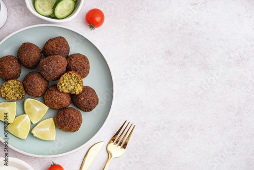 Plate with delicious falafel balls, vegetables and lime on light background photo