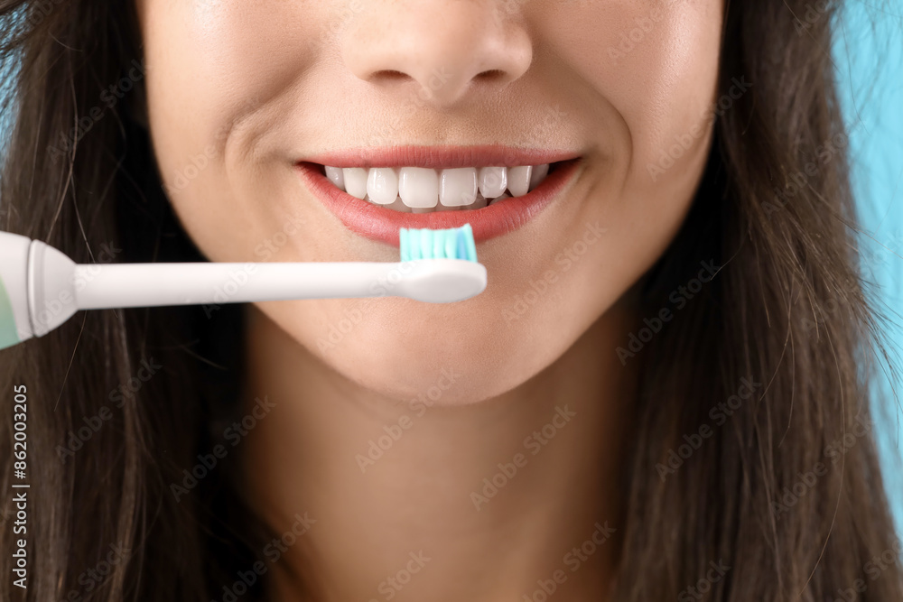 Smiling young woman with electric toothbrush on blue background, closeup Smiling young woman with electric toothbrush on blue background, closeup