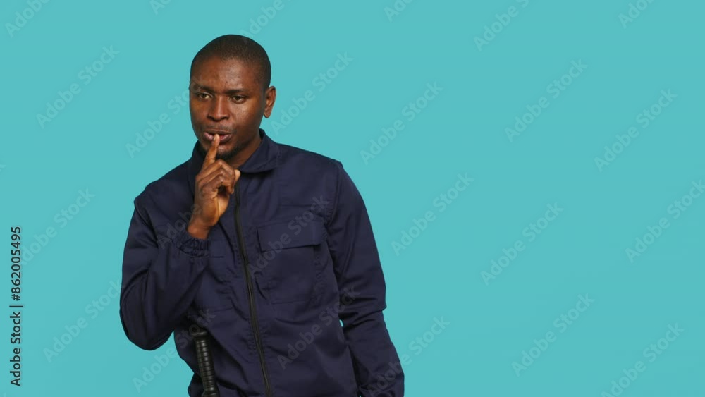 Portrait of security guard doing shush sign gesturing with finger to intruder while overseeing premises. Private law enforcement worker urging people to keep quiet, studio backdrop, camera A Portrait of security guard doing shush sign gesturing with finger to intruder while overseeing premises. Private law enforcement worker urging people to keep quiet, studio backdrop, camera A