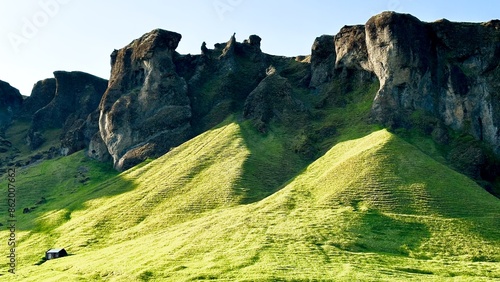 view of large rocky mountain in the middle of grassy field photo