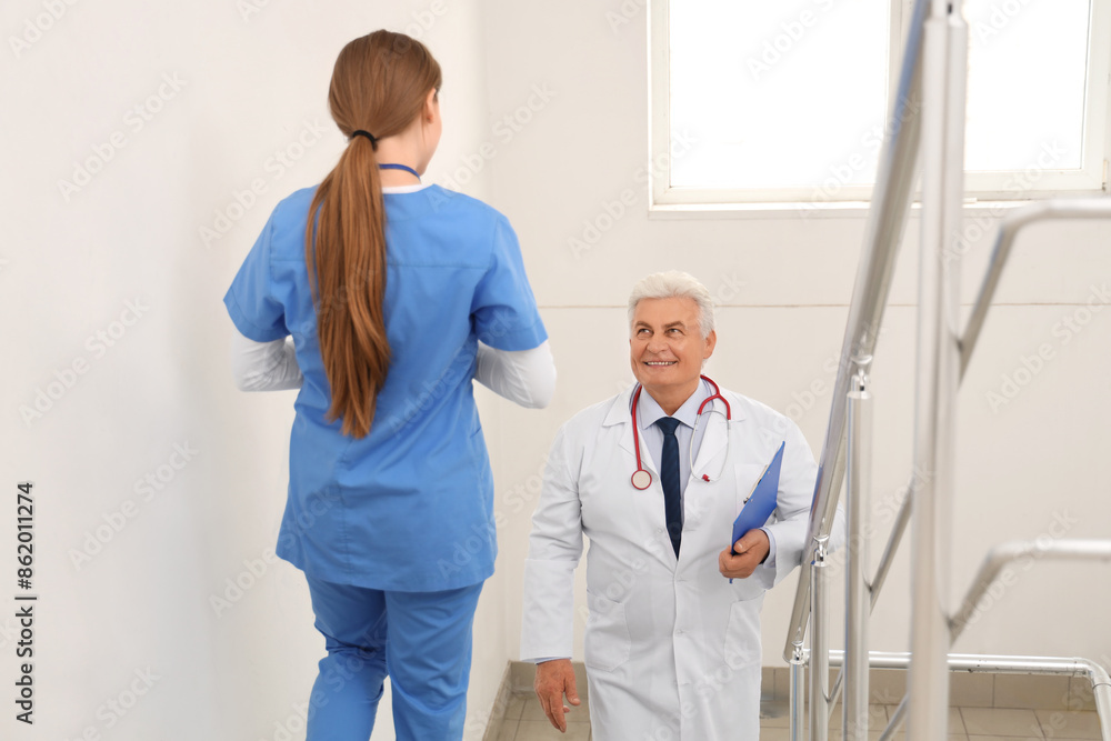 Mature doctor with nurse on stairs in clinic Mature doctor with nurse on stairs in clinic
