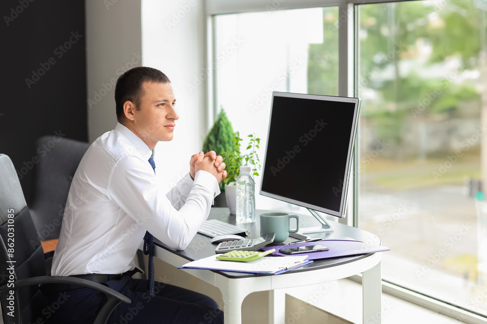 Male accountant sitting at table in office Male accountant sitting at table in office