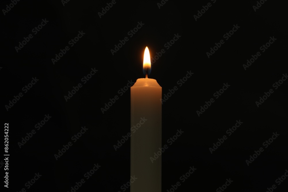 One burning church candle on black background One burning church candle on black background