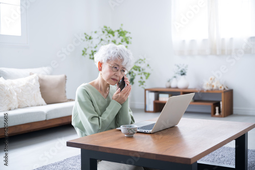 Senior woman talking on phone inquiry while looking at computer Negative image such as difficulty in cancellation Wide angle