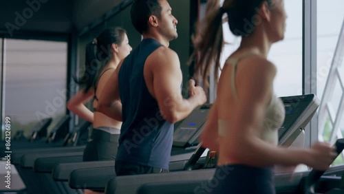 Fit young woman and man running on a treadmill during a workout class at fitness gym