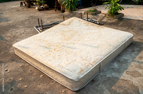 Old mattress on the grass,  cement floor, ,Forgotten, rusty, dirty torn old Mattress, Old discarded mattress on the street. Homelessness or poverty.