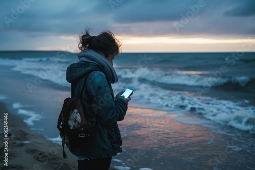 Woman standing on the beach holding a cell phone