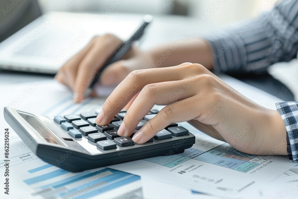 Fototapeta premium Close-up of businesswoman hands using a calculator to check company finances, earnings and budget. Accountant calculating monthly expenses, papers, loan documents, invoices