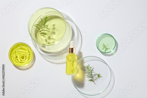 Few petri dishes filled with green and yellow liquid arranged on white background with a serum bottle. Laboratory concept. Container packaging of skin care branding