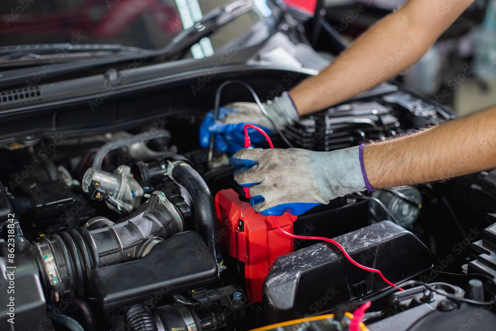 Repairman using handheld digital multimeter of car engine auto mechanic checking battery power of car after been used inside engine. man worker service engine mechanic garage. Repairman using handheld digital multimeter of car engine auto mechanic checking battery power of car after been used inside engine. man worker service engine mechanic garage.