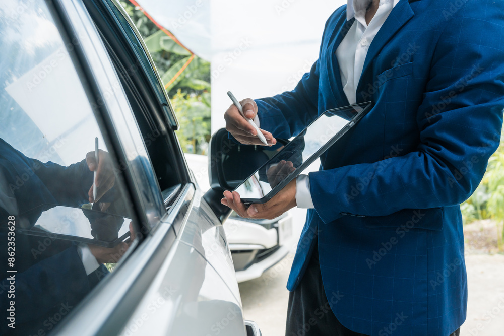 A businessman stands next to his damaged vehicle after an accident, holding a clipboard and examining the scene. An insurance agent arrives to assess the damage and start the claim process. A businessman stands next to his damaged vehicle after an accident, holding a clipboard and examining the scene. An insurance agent arrives to assess the damage and start the claim process.