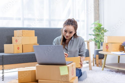 asian young woman owner packing product box prepare to the package for delivery to the customer on sofa at home office asian Entrepreneur SME business concept.