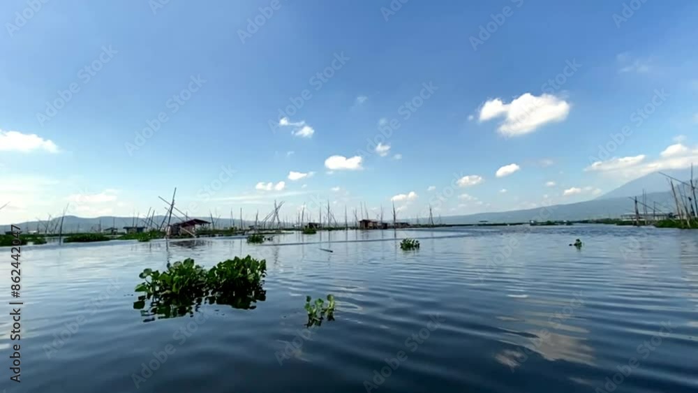 Rawa Pening lake contains water hyacinth plants against a backdrop of mountains and blue sky and white clouds Rawa Pening lake contains water hyacinth plants against a backdrop of mountains and blue sky and white clouds