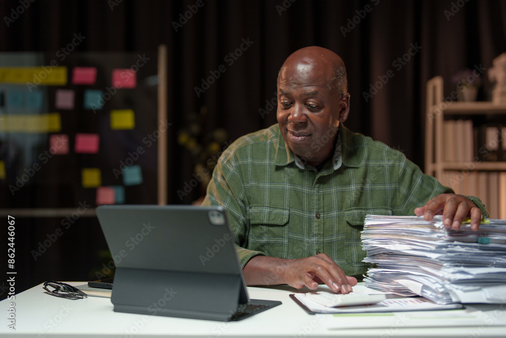 Retired businessman, personal business is checking, checking documents, searching for financial reports. Analyze online data in the office Sitting at the desk in front of the laptop. Retired businessman, personal business is checking, checking documents, searching for financial reports. Analyze online data in the office Sitting at the desk in front of the laptop.