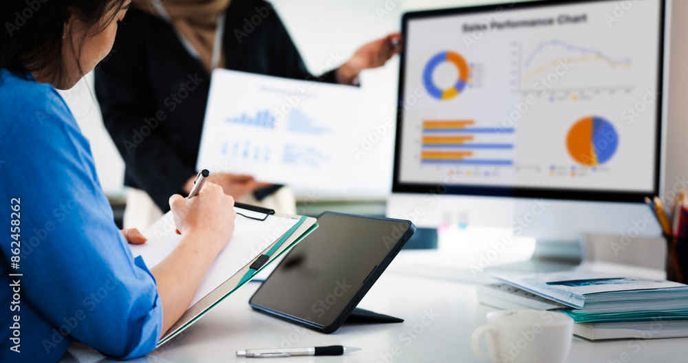 Two businesswoman pointing to graphs and charts to analyze market data, net profit to plan new sales strategy to increase production capacity. Two businesswoman pointing to graphs and charts to analyze market data, net profit to plan new sales strategy to increase production capacity.