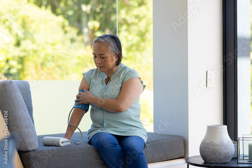 Senior woman measuring blood pressure with digital monitor at home