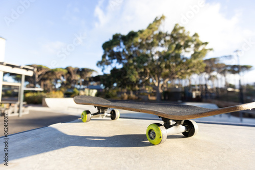 Skateboard resting on ledge at outdoor skate park on sunny day, copy space