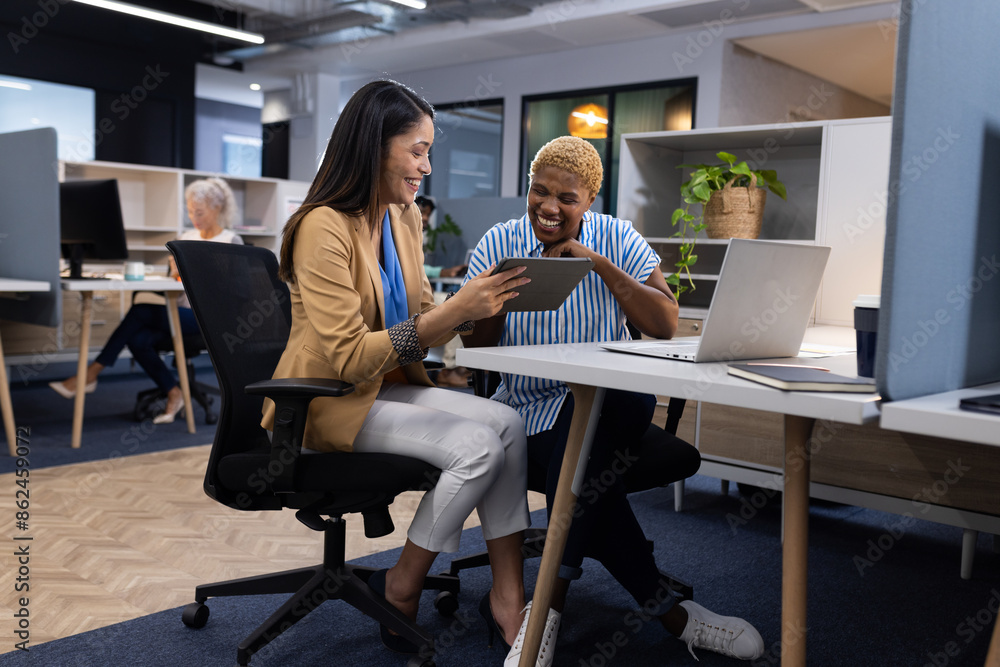 Collaborating in modern office, female showing tablet to male colleague Collaborating in modern office, female showing tablet to male colleague