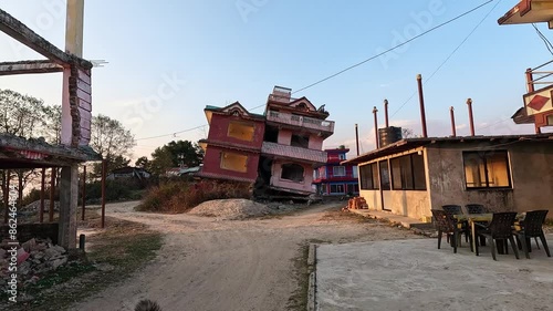 Sheppard dog in front of a earthquake destroyed house in Chisapani, Nepal. Hotel lodge standing tilted by earthquake photo