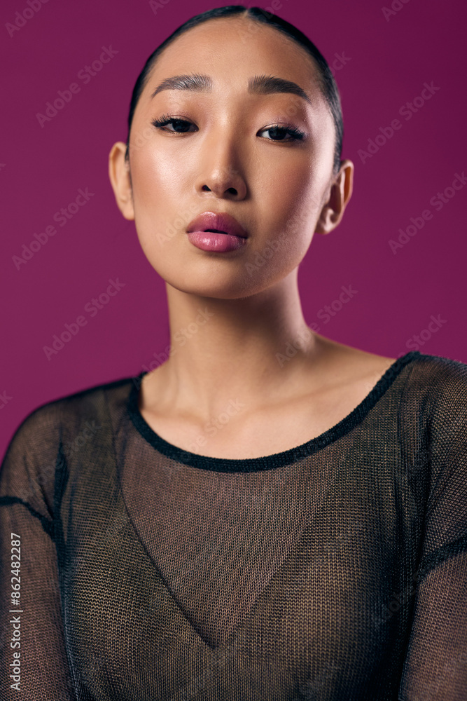 Fashion asian woman in sheer top posing against purple background with eyes closed and pink lipstick on lips Fashion asian woman in sheer top posing against purple background with eyes closed and pink lipstick on lips