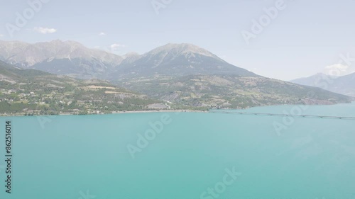 Savines Bridge Spanning Over The Turquoise Of Lake Serre Poncon In France. wide, panning shot photo