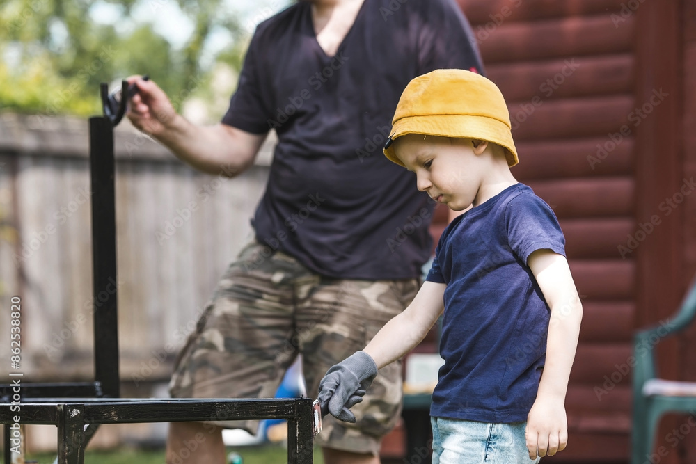 Father and son work with a brush and apply black paint to the rust. People paint metal structures. Rust removal. Teaching a child to work. Father and son work with a brush and apply black paint to the rust. People paint metal structures. Rust removal. Teaching a child to work.