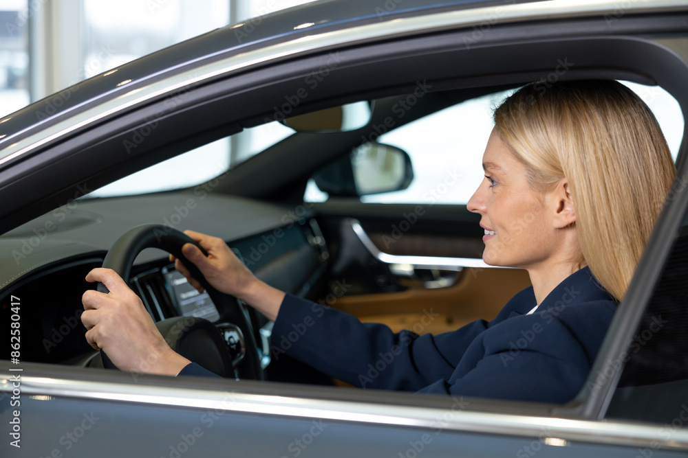 Confident blonde woman sitting in a car and looking determined