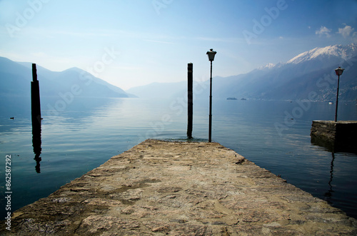 Pier and Snow Capped Mountain on the Waterfront  to Lake Maggiore with Brissago Islands in a Sunny Day in Ascona, Ticino, Switzerland. photo