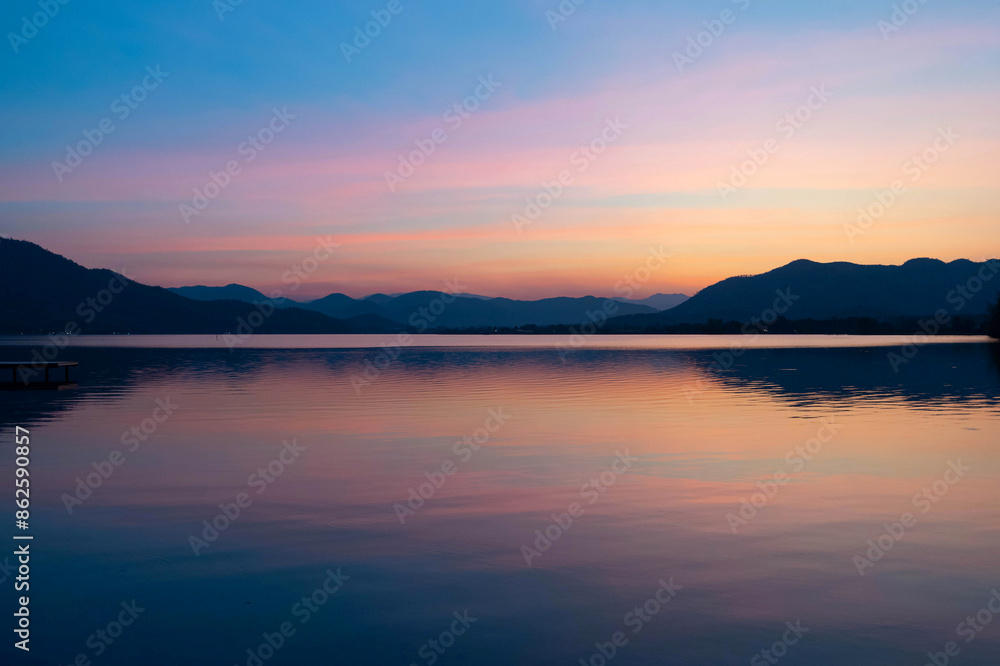 Background image of the Reservoir. Beautiful sunrise or sunset sky over calm lake with reflection in surface water in the morning or evening. copy space. Lam Taphen Reservoir, Suphanburi. Background image of the Reservoir. Beautiful sunrise or sunset sky over calm lake with reflection in surface water in the morning or evening. copy space. Lam Taphen Reservoir, Suphanburi.