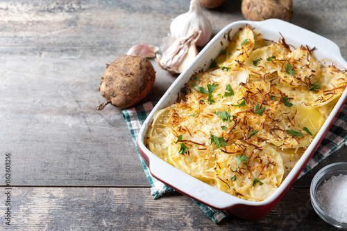Potato gratin baked with cream and cheese on wooden table. Copy space photo