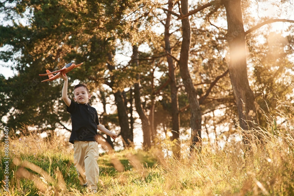 Running with toy plane. Little boy is having fun outdoors at summertime Running with toy plane. Little boy is having fun outdoors at summertime