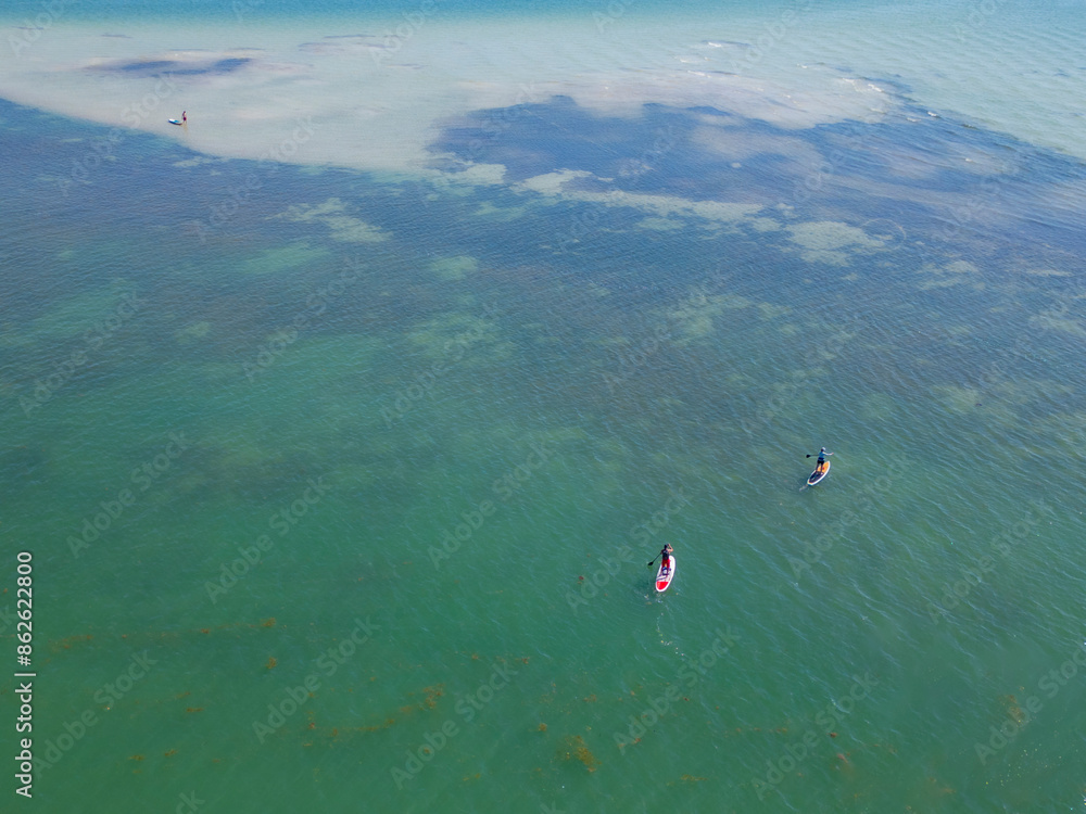 Aerial view of three people paddleboarding in calm ocean waters, Hurricane Pass, Dunedin, Florida, United States. Aerial view of three people paddleboarding in calm ocean waters, Hurricane Pass, Dunedin, Florida, United States.