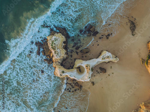 Aerial view of Praia dos Tres Castelos with rock formations and azure ocean waves, Faro, Portugal. photo