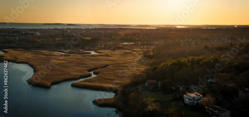 Aerial view of serene river, peaceful forest, and suburban houses at dusk in Milton, Massachusetts, United States. photo